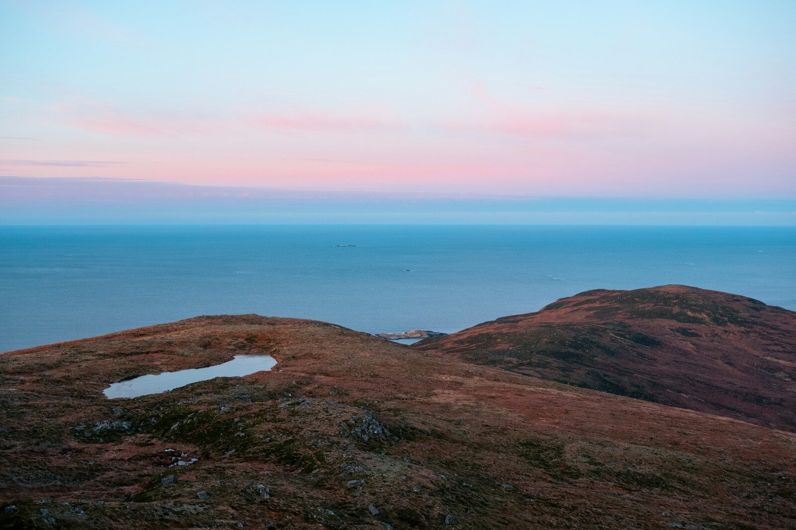 Hills and ocean under a pastel sky.